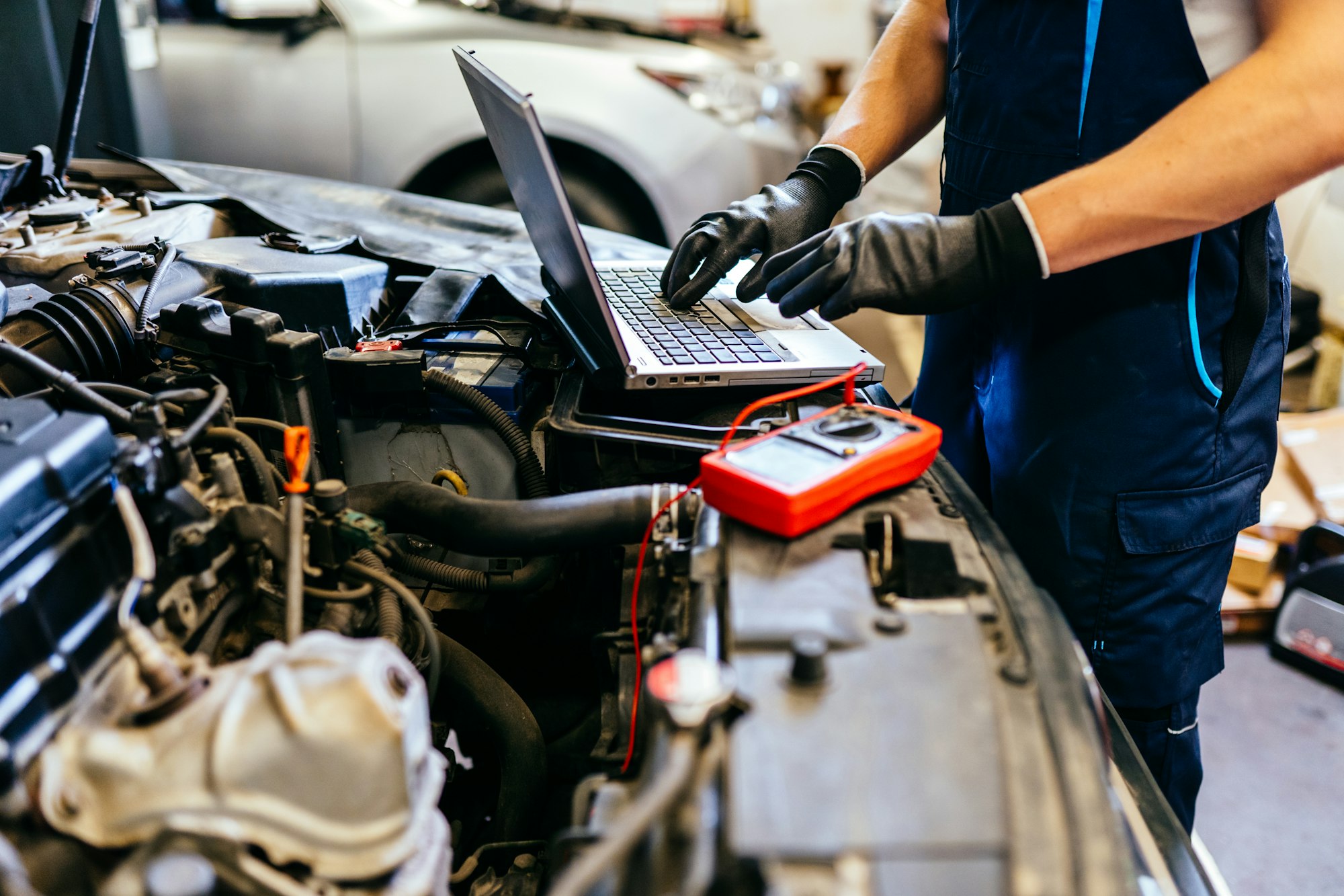 Car mechanic at work. Car an electrician using computer in auto repair shop. Close up.