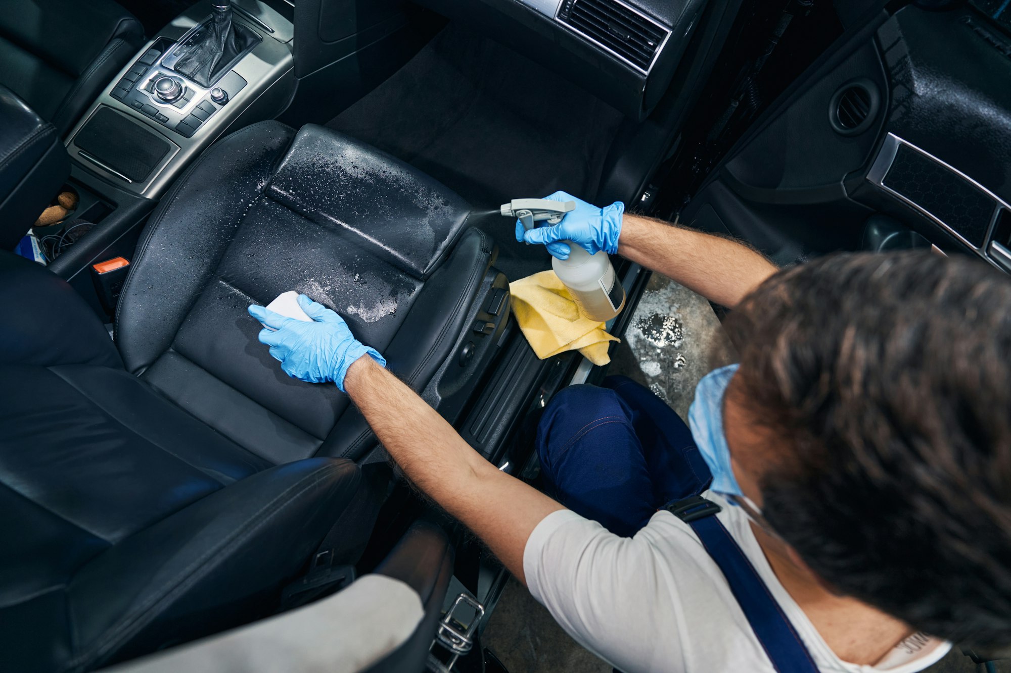 Car service employee cleaning front seat of automobile