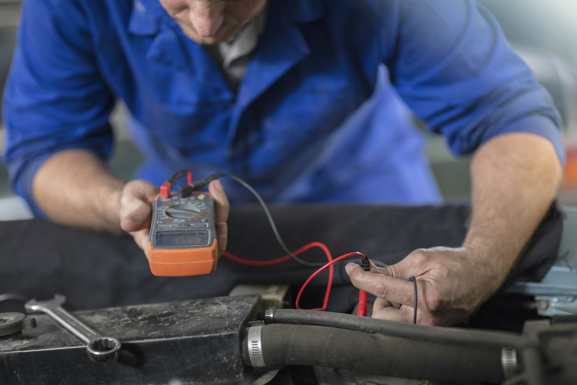 Mechanic using a multimeter on a vehicle.